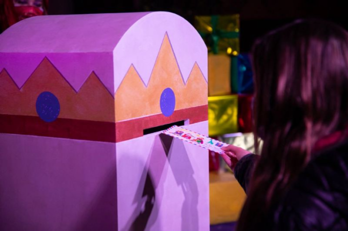 Una niña deposita una carta en un buzón mágico (Ayuntamiento de Castelldefels)