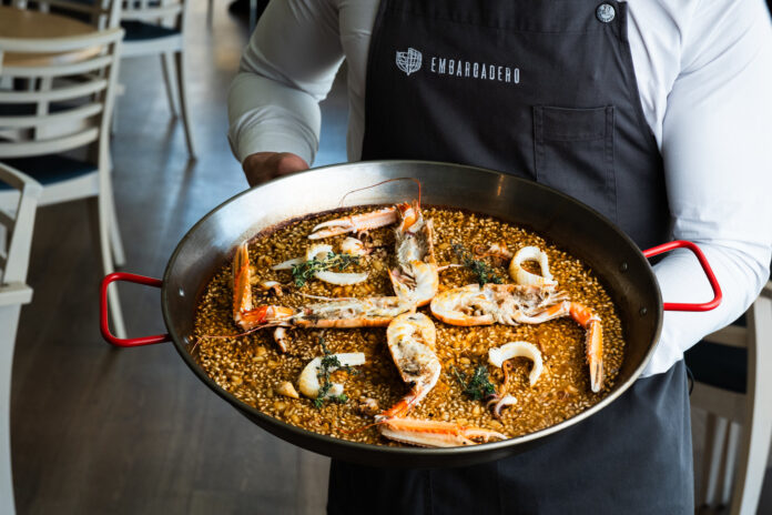 Un camarero del restaurante Embarcadero con un arroz elaborado con producto fresco, uno de los platos emblemáticos de la cocina mediterránea del Grupo Lancaster.